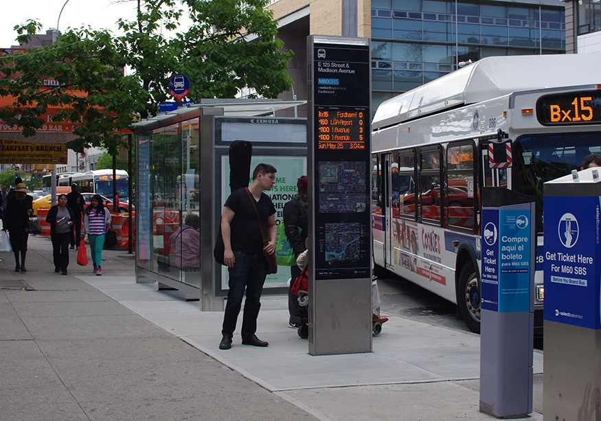 People using WalkNYC Real-Time Bus Arrival sign